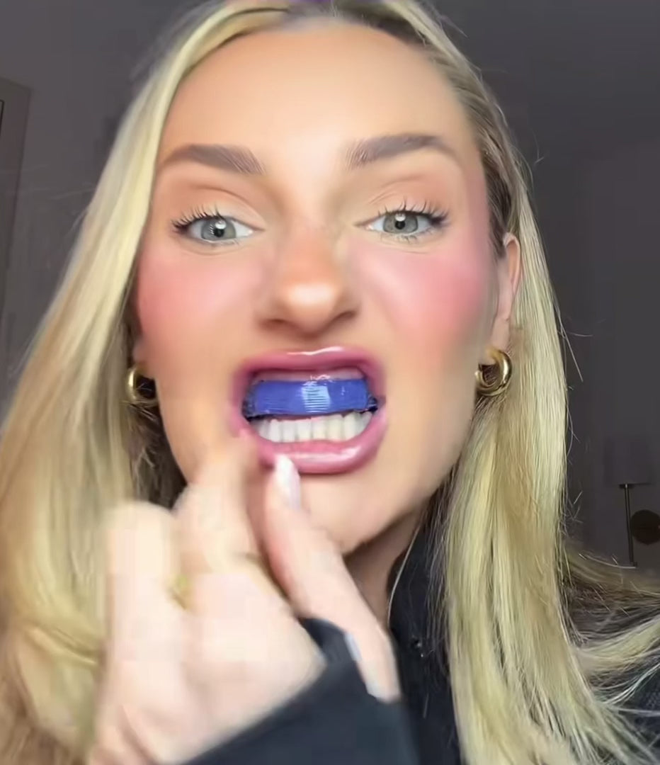 Woman applying Wellio purple teeth whitening strip to upper teeth